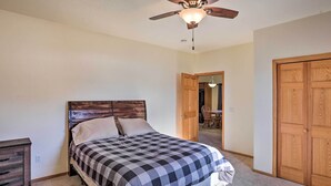 Ein Schlafzimmer mit einem Bett, einem Holz-Kopfteil, einem Deckenventilator und einer Holztür.