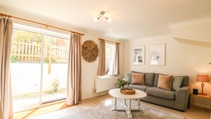 A living room with a grey sofa, a white coffee table, and a view of a wooden fence outside.