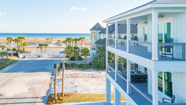 A beachfront property with a multi-level structure, a covered outdoor seating area, and a view of the ocean.