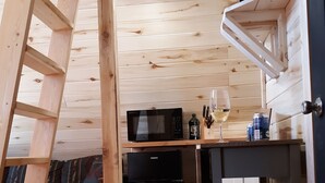 Una cocina compacta con microondas, refrigerador y estantes de madera.