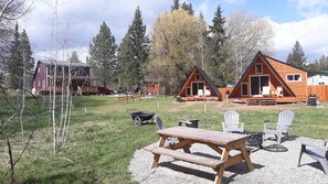 En campingplads med træhytter, et picnicbord og udendørs siddepladser.