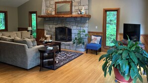 A living room with a stone fireplace, a sofa, a coffee table, and a potted plant. - Romantic Mountain house with views (Fairview)