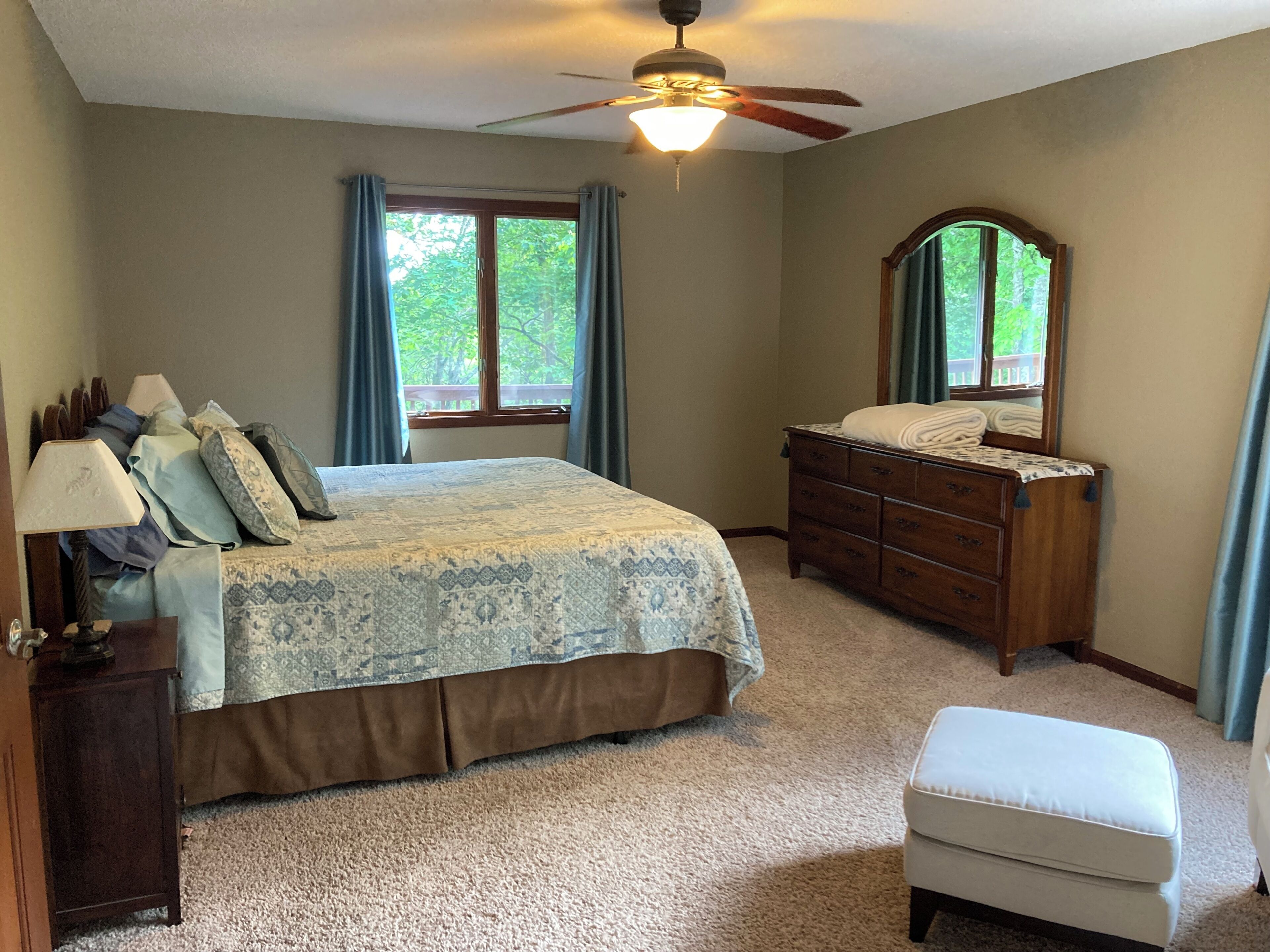 A bedroom with a bed, dresser, nightstand, and a ceiling fan.