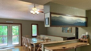 A dining area with a wooden table and chairs, a ceiling fan, and a painting of mountains. - Romantic Mountain house with views (Fairview)