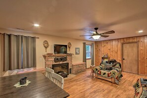 Ein gemütliches Wohnzimmer mit Kamin, Holzwänden, Deckenventilator und Fernseher.
