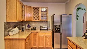 Une cuisine avec des meubles de rangement en bois, un réfrigérateur en acier inoxydable, un grille-pain et une plante décorative.