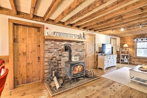 A rustic interior with a brick fireplace, wooden beams, a TV, and a sign reading "Chatham NH". - Black Bear Lodge: A Rural White Mtns Retreat (Chatham)