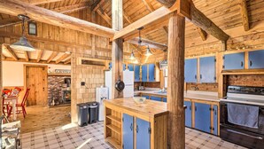 Eine rustikale Küche mit Holzsäulen, einer zentralen Kochinsel und einer Ziegelwand.