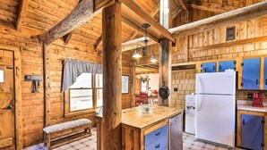 Innenansicht einer Holzhütte mit Küchenzeile, Holzwänden, einer Bank und einem Kühlschrank.