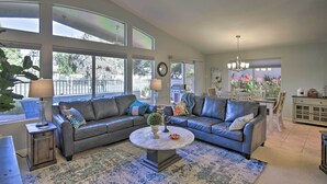 A spacious living room with a sectional sofa, a round coffee table, and large windows providing natural light. - Snowbird & Golfer Oasis! Lake-View Peoria Retreat (Surprise)