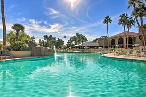 Une piscine d’un bleu éclatant, avec des chaises longues et des palmiers.