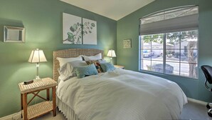 A bedroom with a large bed, two bedside tables with lamps, a ceiling fan, and a window with a view of the outside. - Snowbird & Golfer Oasis! Lake-View Peoria Retreat (Surprise)