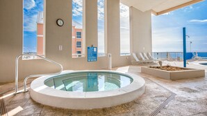 Ein Poolbereich mit Whirlpool, Liegestühlen und Blick aufs Meer.