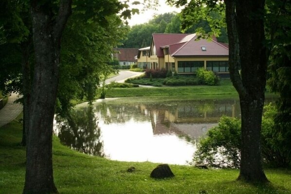 A house with a pond in front, surrounded by trees.