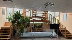 A room with a wooden staircase, a large window, and a bed.