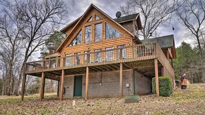A log cabin with a balcony, a stone foundation, and a green door. - Fire Pit + Views: Family Cabin on Table Rock Lake (Golden)