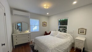 Une chambre à coucher avec un grand lit, une commode, une table de chevet, un miroir et une fenêtre.