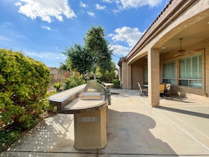 A patio area with a built-in grill, outdoor seating, and a view of the surrounding neighborhood.