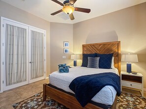 A bedroom with a bed, two bedside tables, a ceiling fan, and a large closet.