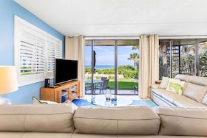 Ein Wohnzimmer mit Fernseher, Sofa und Glastisch.