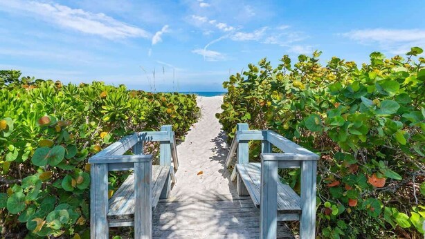 A wooden pathway leading to a beach with a clear sky.