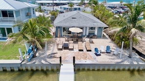 A beachfront property with a covered patio, outdoor seating, and a pool.