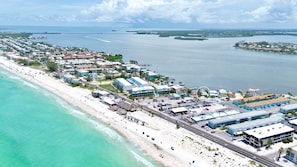 An aerial view of a coastal area with a beach, buildings, and water.
