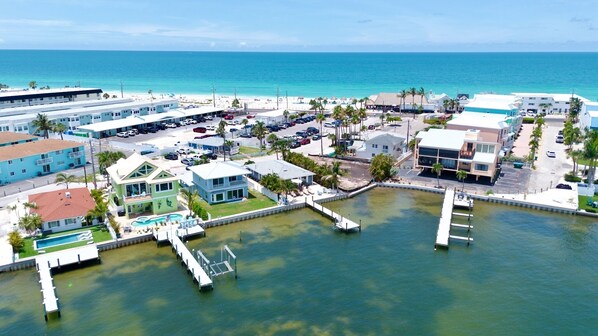 An aerial view of a coastal town with a marina, buildings, and a beach.