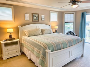 Une chambre à coucher avec un lit, des tables de chevet et un ventilateur de plafond.