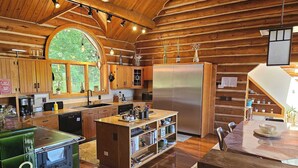 A spacious kitchen with wooden cabinets, a large island, and a stainless steel refrigerator. - Vinewood Estate Luxury Pool and Vineyard Retreat (Hillsboro)
