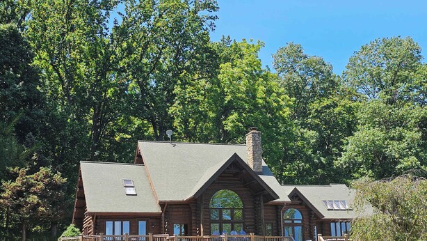 A large log cabin with multiple balconies, a stone chimney, and a well-maintained lawn. - Vinewood Estate Luxury Pool and Vineyard Retreat (Hillsboro)