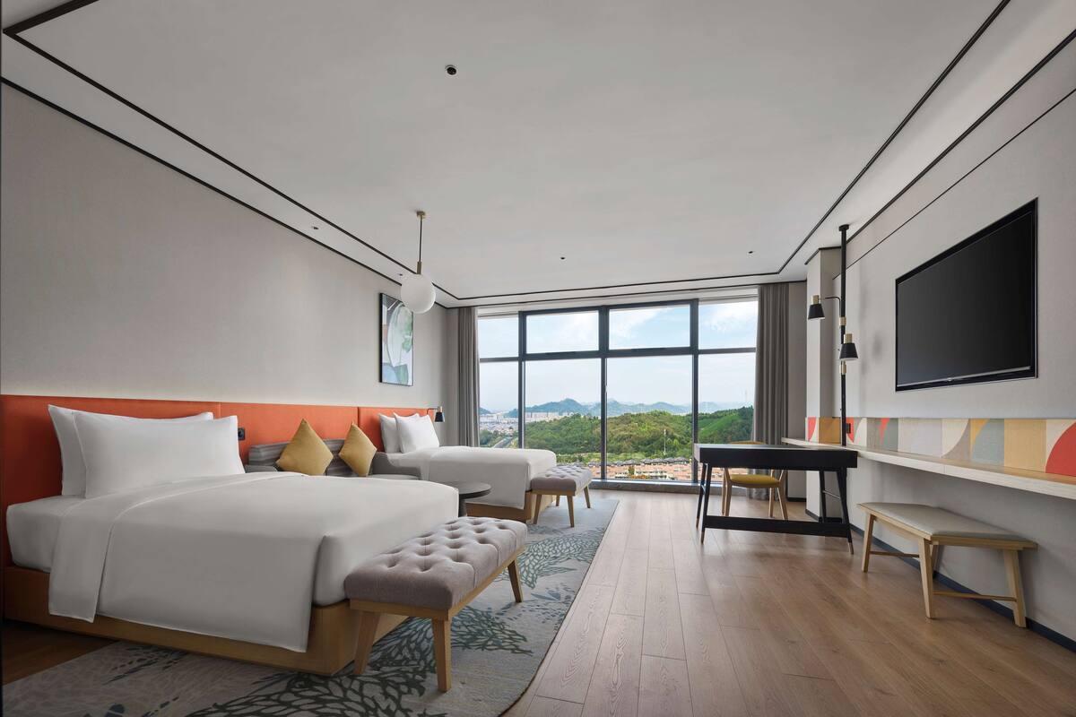 Una habitación de hotel moderna con una cama grande, un escritorio y un televisor.