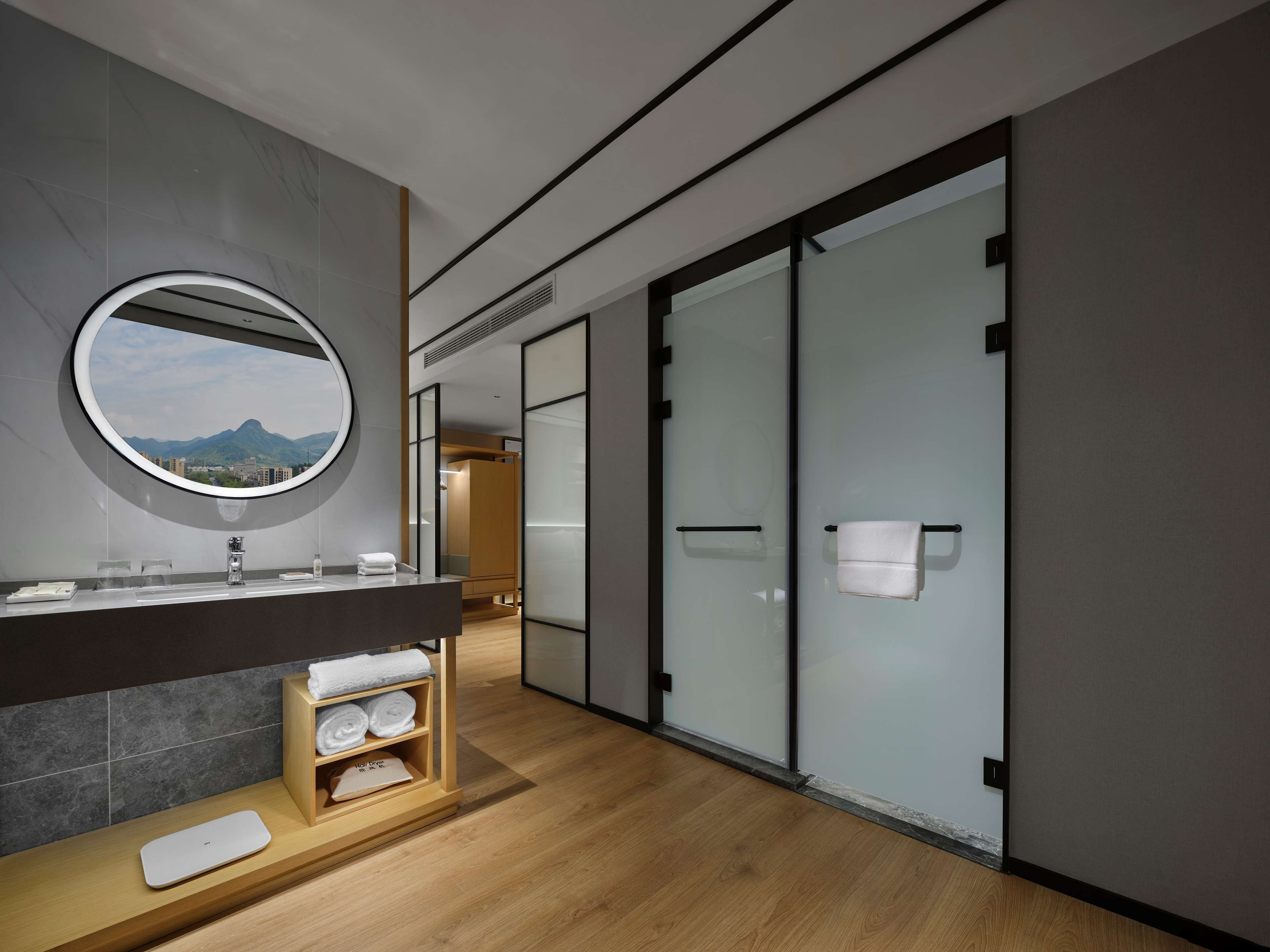 Un bagno moderno con uno specchio grande, un mobile vanitario in legno e vista sulle montagne dalla finestra.