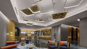 Un hall d’entrée moderne avec des espaces de détente, un comptoir d’accueil et un bar.