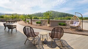 Une terrasse sur le toit, aménagée avec des meubles en osier, un fauteuil suspendu et des plantes en pot.