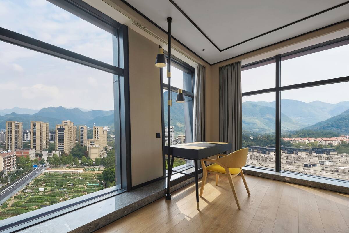 Una habitación moderna con ventanas amplias, una mesa de comedor y una silla.