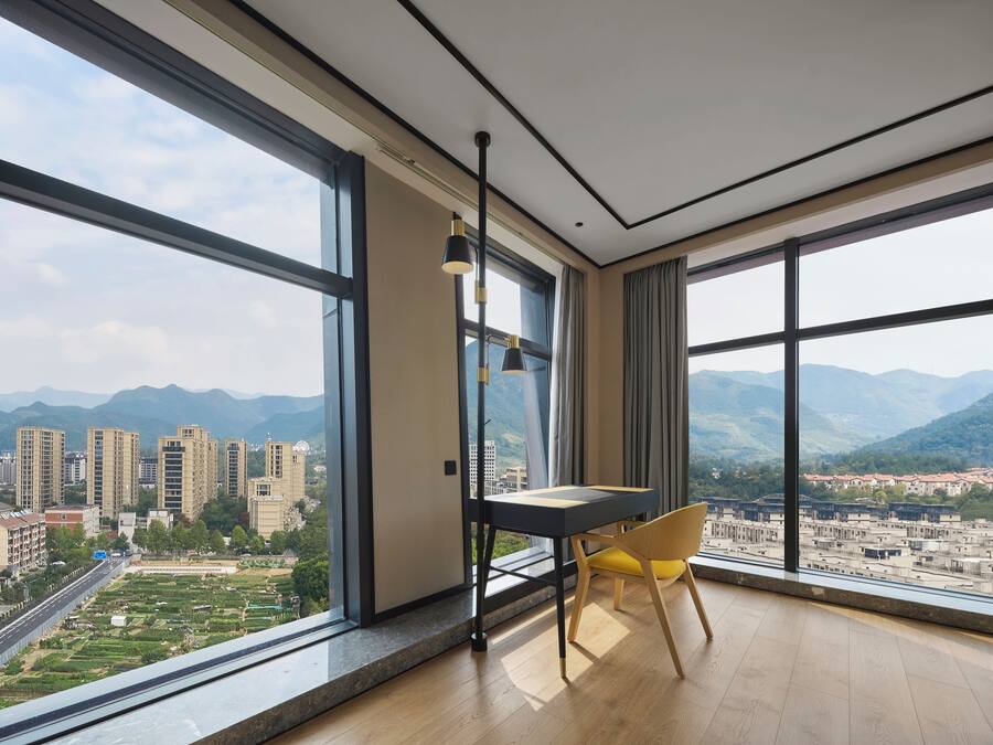 Una habitación moderna con ventanas amplias, una mesa de comedor y una silla.