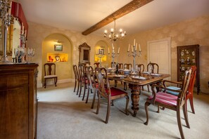 A dining room with a wooden table, chairs, and a chandelier. There are wall sconces and a mirror above the table. - Ivy Farm, Grimston, Norfolk (Grimston)