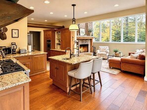 A spacious kitchen with a central island, wooden cabinets, and a fireplace. - The Manor - Modern Farmhouse with Hot Tub (West Dover)