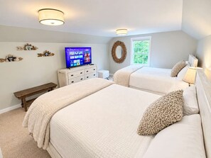 Un dormitorio con dos camas, un televisor, un aparador y una ventana.