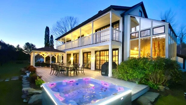 Una casa de dos pisos con un jacuzzi en el jardín trasero.