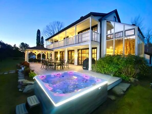 Una casa de dos pisos con jacuzzi y zona de estar al aire libre.