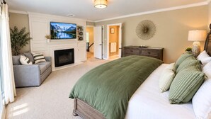 Un dormitorio con cama, televisión, chimenea y vista a la montaña.