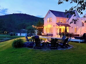 Une maison à deux étages dotée d’un patio aménagé avec des meubles d’extérieur et un foyer.
