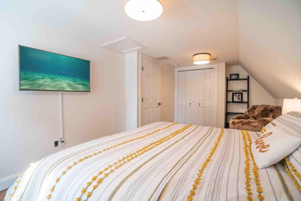 Un dormitorio con cama, un cuadro, un armario y una estantería con un marco de fotos.