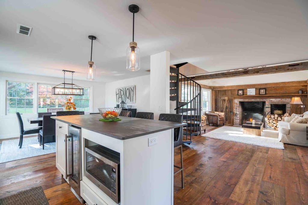 Una cocina moderna con una isla central, un área de comedor con vistas y una sala de estar acogedora con chimenea.