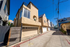 Une rue résidentielle bordée de maisons, avec une clôture en bois et un ciel dégagé.