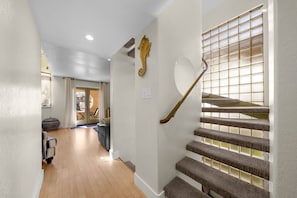 Un couloir menant à un escalier doté d’une rampe en bois et agrémenté d’une décoration murale représentant un hippocampe.