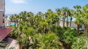 Un hôtel doté d’une piscine entourée de palmiers et offrant une vue sur l’océan.