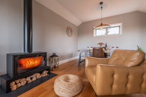 A cozy living room with a modern fireplace, leather sofa, and a dining area with a table and chairs.